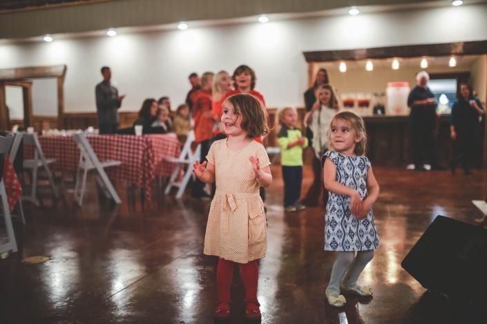Two children dancing in a banquet hall with tables and guests in the background