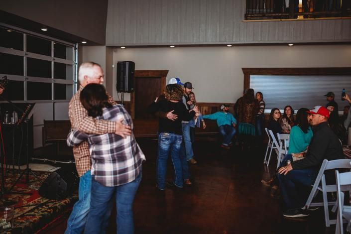 Couple slow dancing in a hall while guests sit and watch nearby