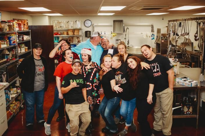 Group of people posing together in a cluttered shop, smiling and making playful gestures.