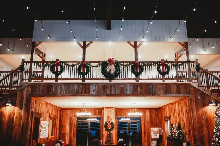 Festive wooden lodge with balcony wreaths and string lights at night