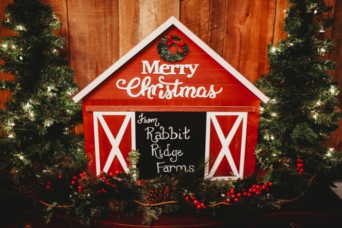 Red wooden Christmas barn sign with white “Merry Christmas” lettering and “from Rabbit Ridge Farms” on black board