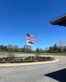 American flag and a white flag on poles beside a curved driveway under a clear blue sky