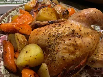 Roasted chicken with potatoes, carrots, and vegetables on a serving platter