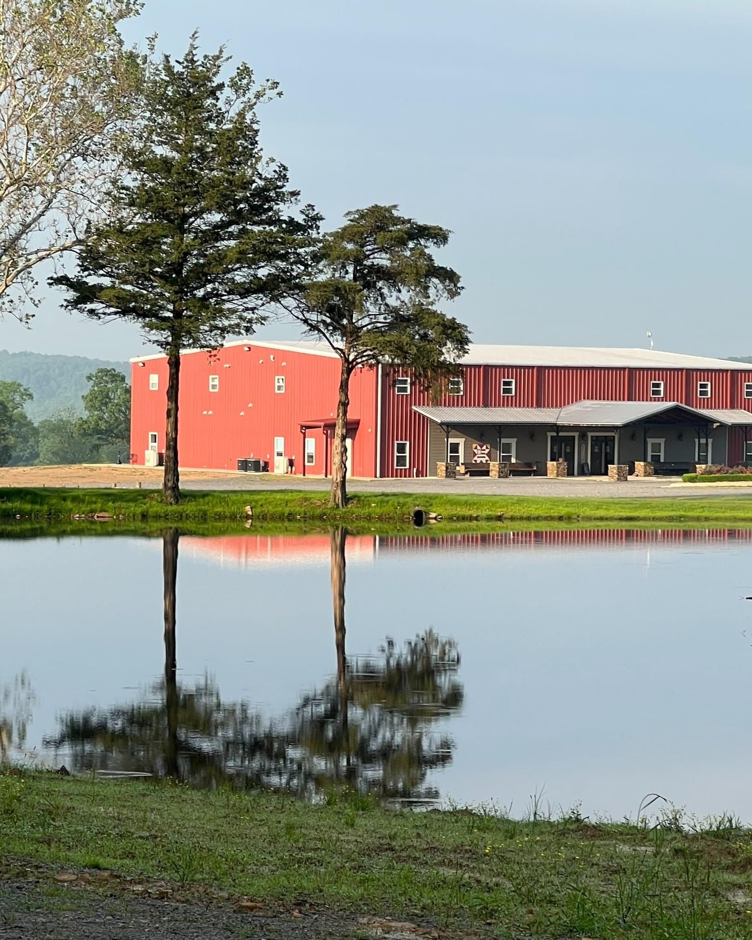 Red building by a pond, with trees and a clear reflection in the water.