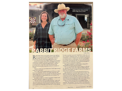 Two people standing outside Rabbit Ridge Farms, with text and a farm sign below.