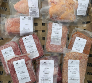 Vacuum-sealed meats and seafood packages arranged on a wooden pallet.