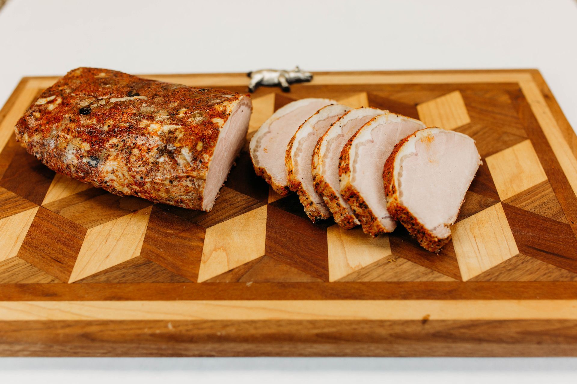 Sliced roasted meat loaf on a wooden cutting board with a chef’s knife