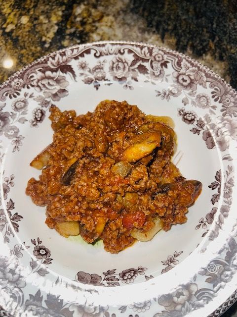 Plate of chunky meat sauce or stew on a white floral dish