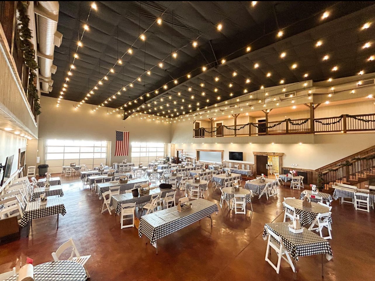 Elegant banquet hall with white tables and chairs under a string-lit ceiling