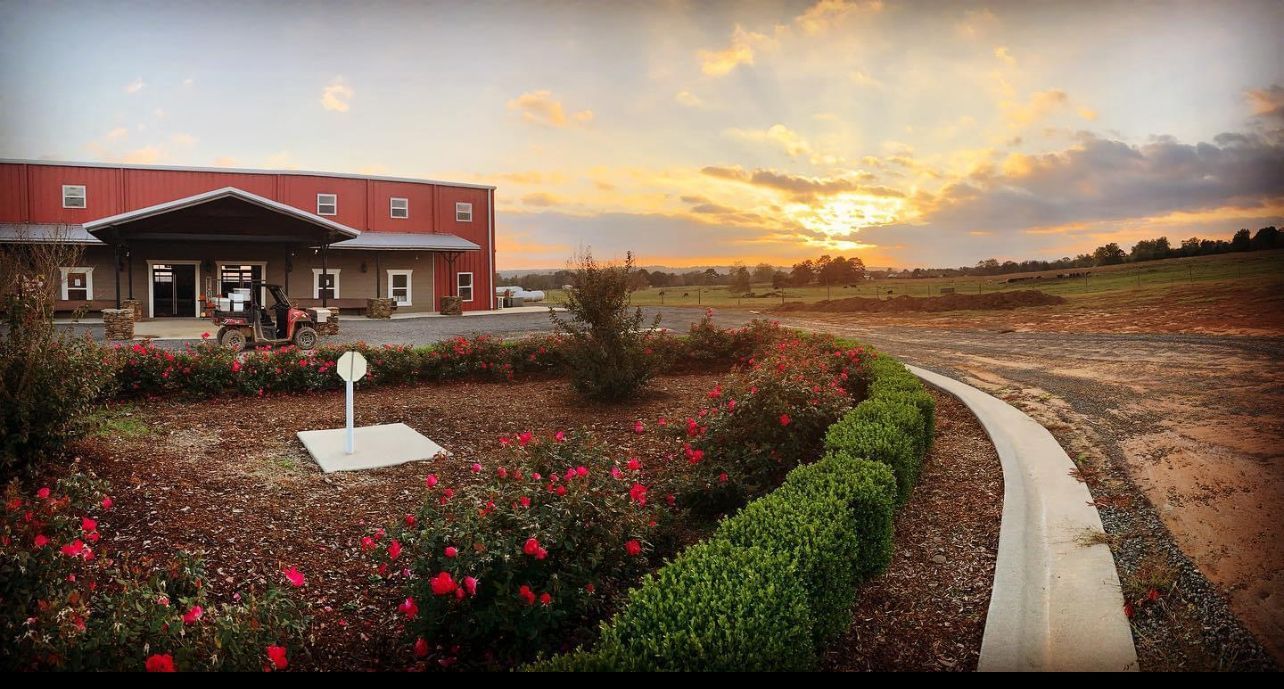 Red house beside a curved path and flower bed at sunset