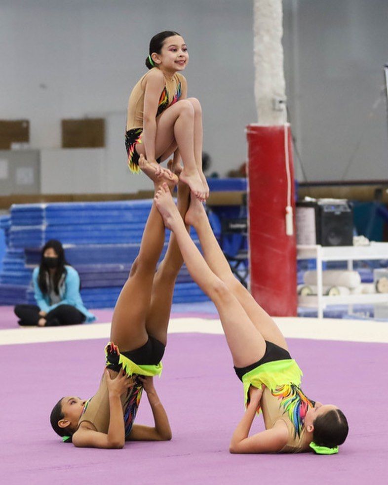 A gymnast is sitting on a balance beam covered in chalk.