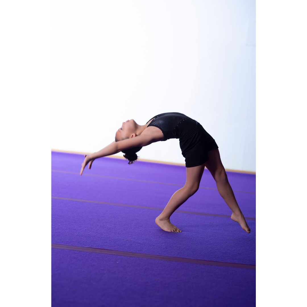 A gymnast is sitting on a balance beam covered in chalk.