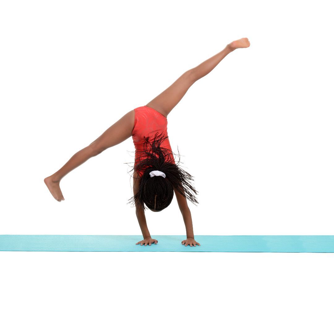 A young girl is sitting on a balance beam in a gym.