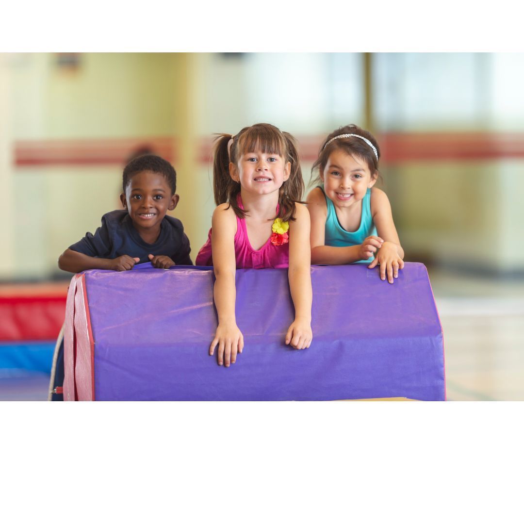 A young girl is playing with a blue ball on a yoga mat.