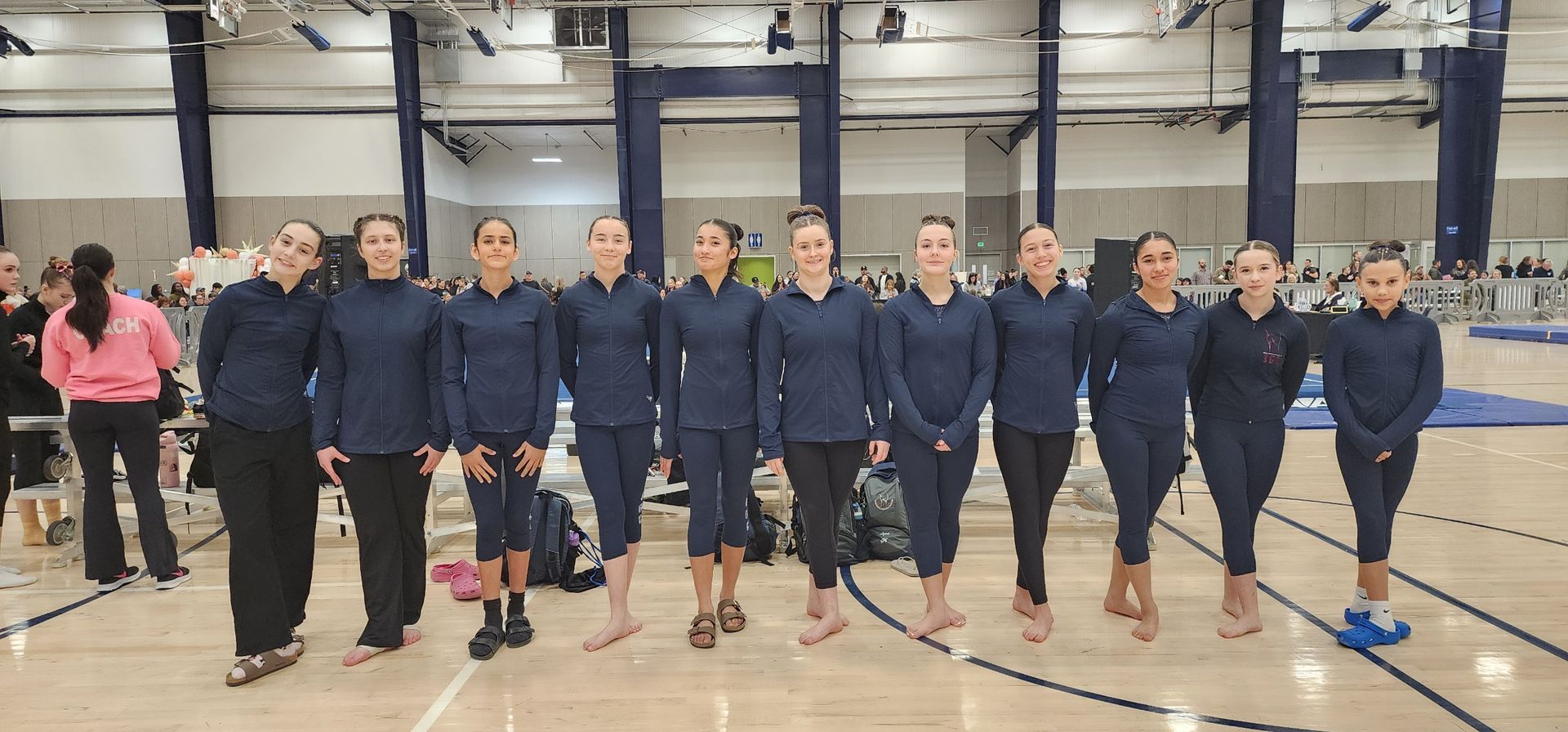 Group of people in navy jackets standing in a row on an indoor court