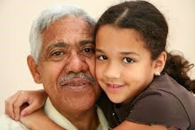 An older man and a young girl are hugging each other.