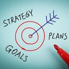 A red marker is pointing at a target with the words `` strategy goals plans '' written on it.