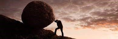A man is pushing a large rock up a hill.