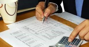 A person is writing on a piece of paper while using a calculator.