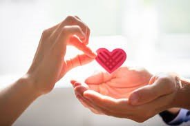 A person is holding a paper heart in their hands.