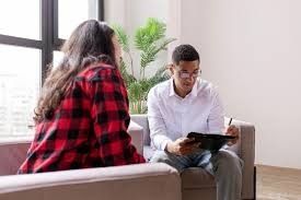 A man is sitting on a couch talking to a woman.