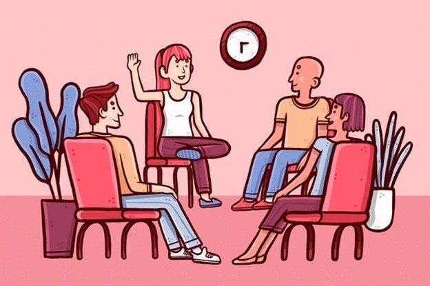 A group of people are sitting in chairs in a circle talking to each other.