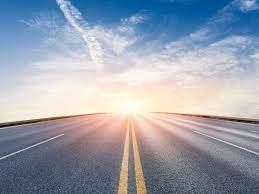 The sun is shining through the clouds on the road.