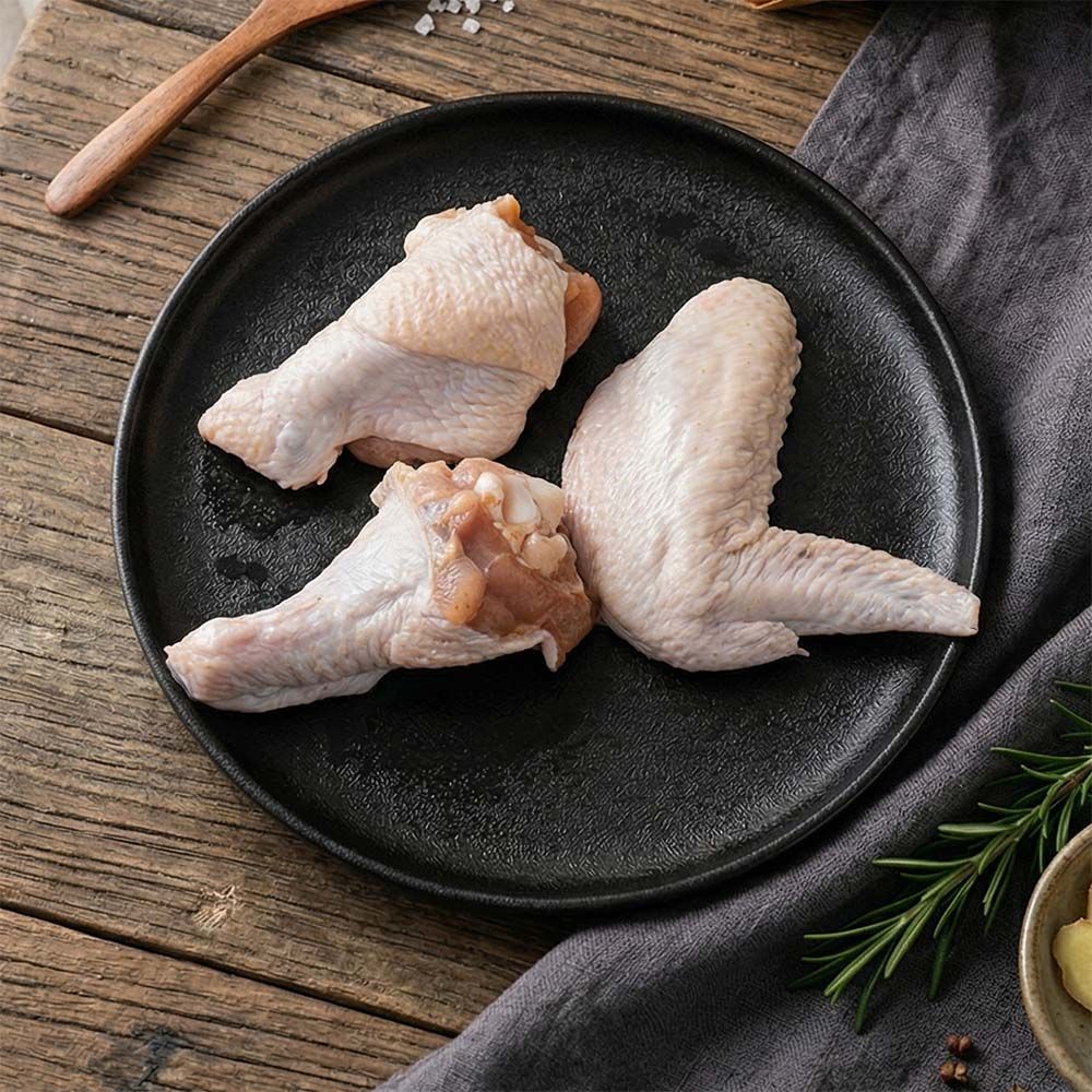 Raw chicken pieces with vegetables on a wooden cutting board.