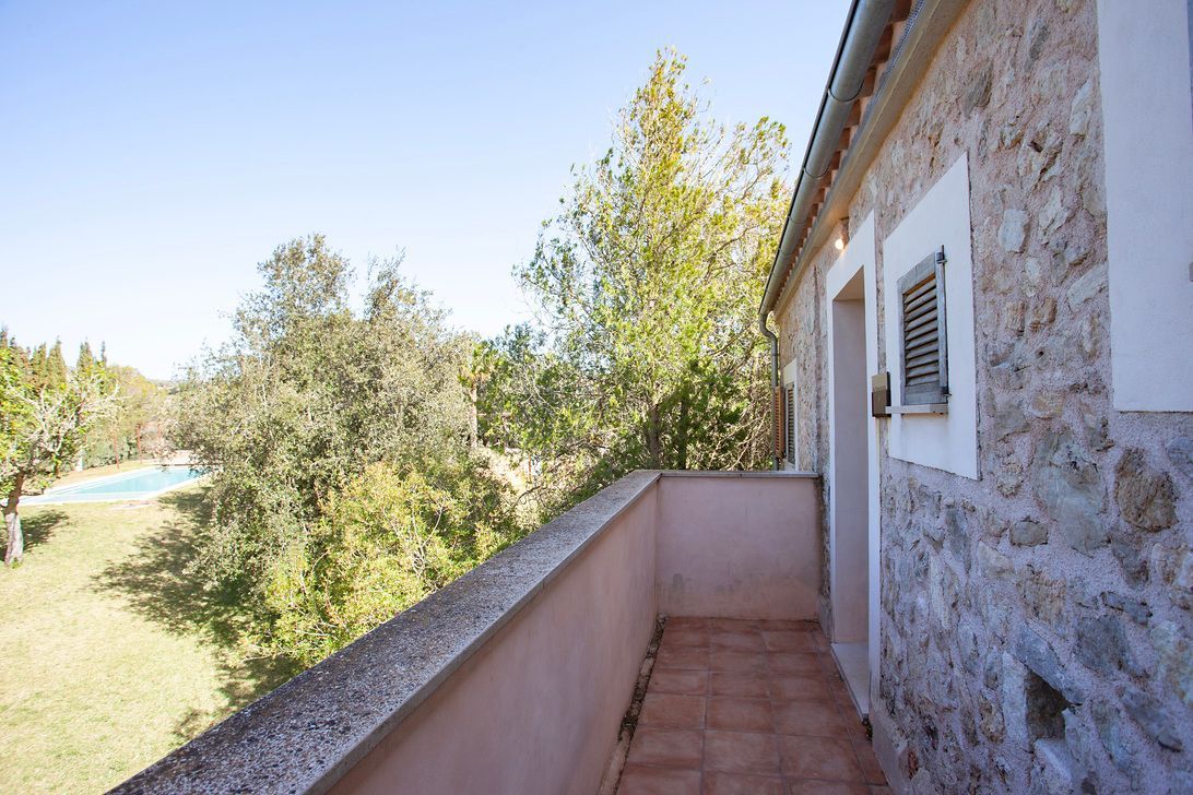 Un balcón con vista a la piscina y a los árboles.