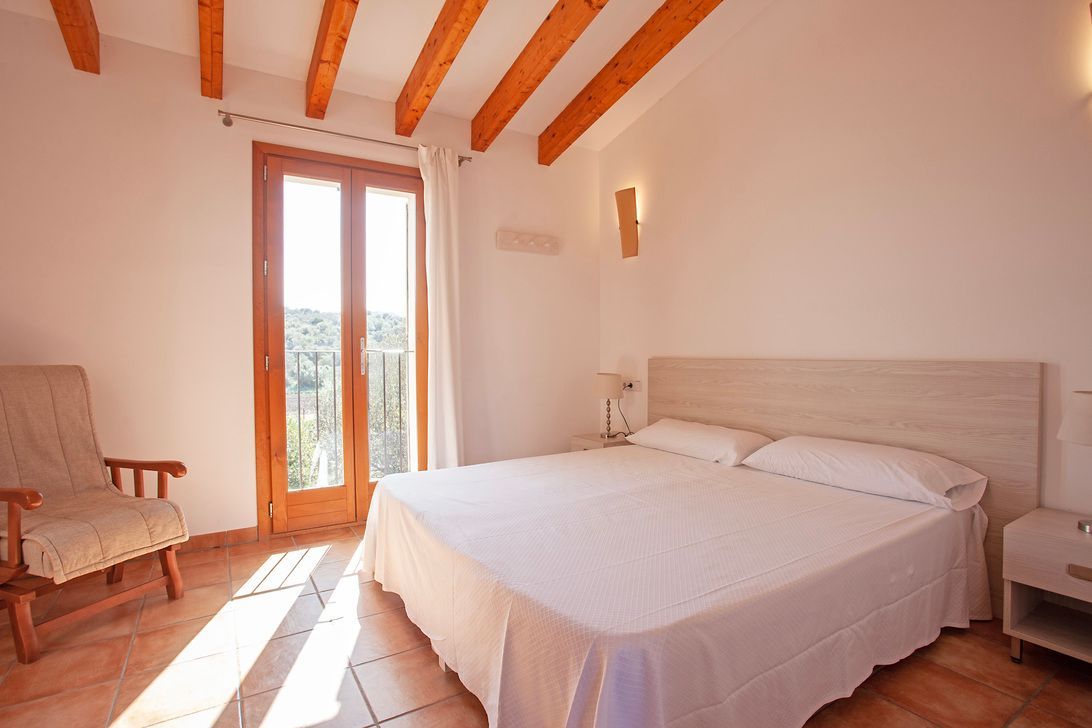 Un dormitorio con una cama grande y una silla.