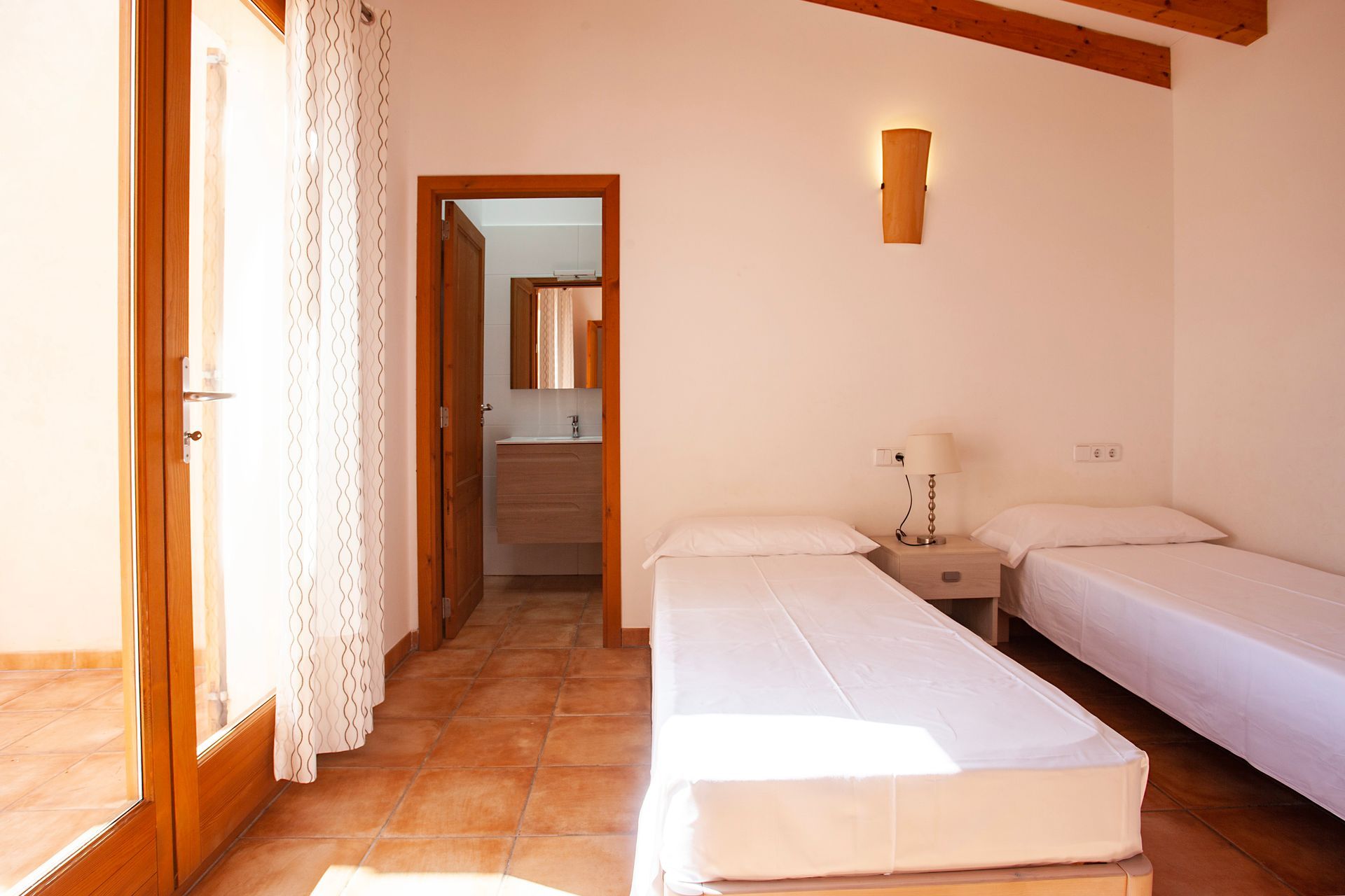 A bedroom with two beds and a door leading to a bathroom