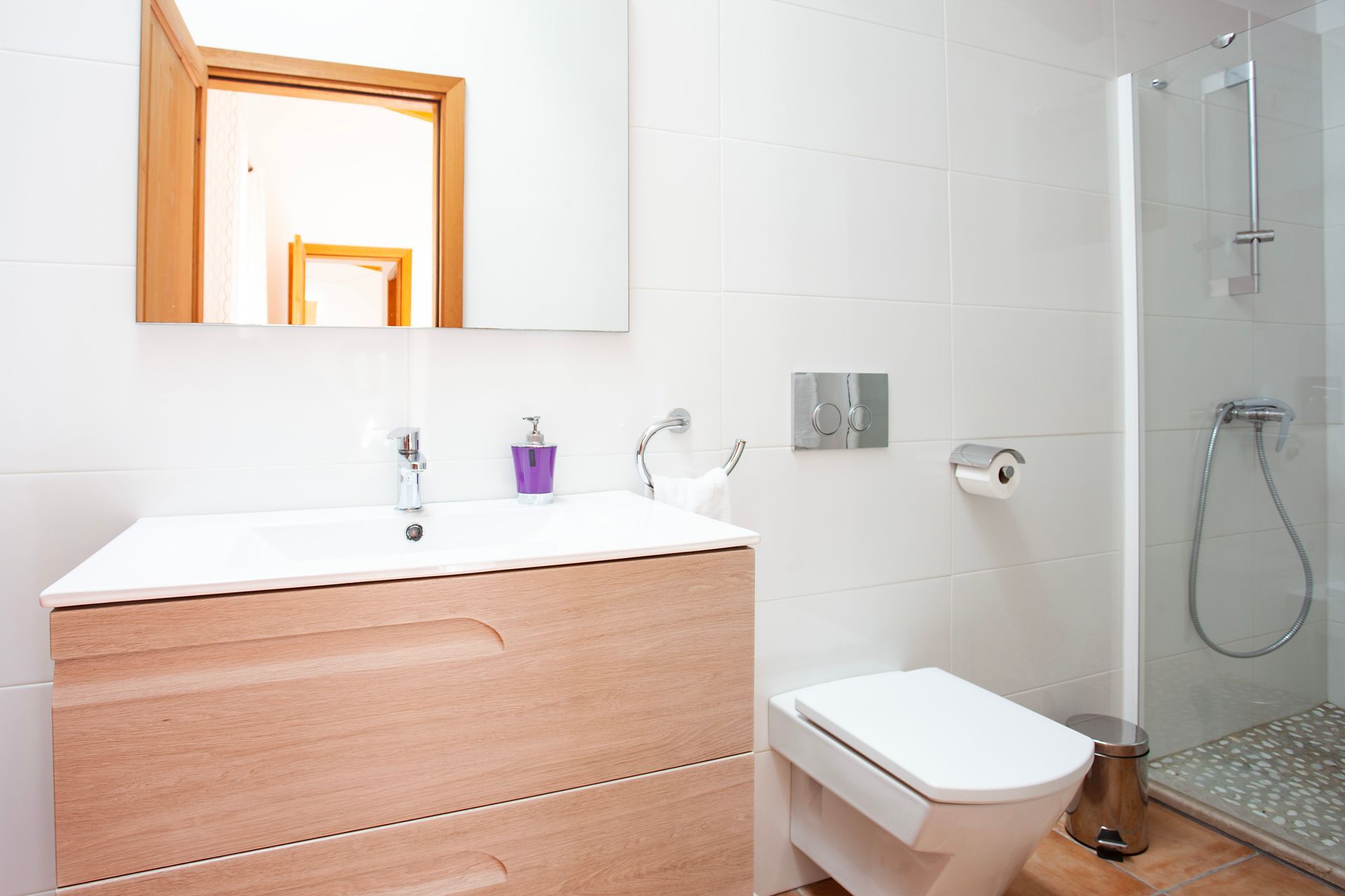A bathroom with a toilet , sink , mirror and shower.