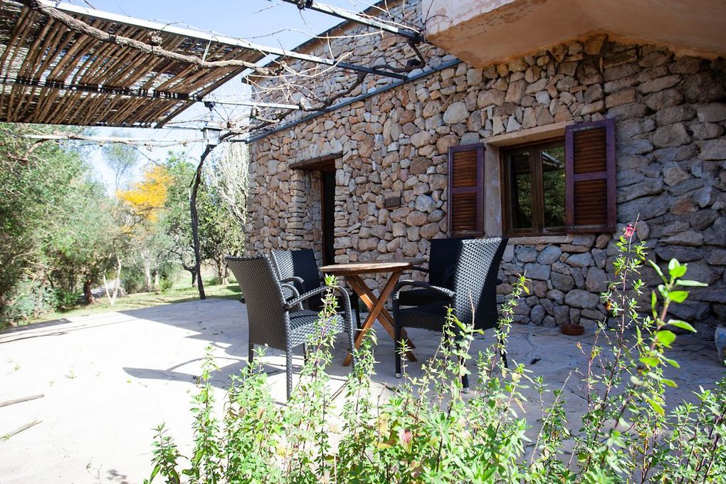 Un edificio de piedra con una mesa y sillas delante.