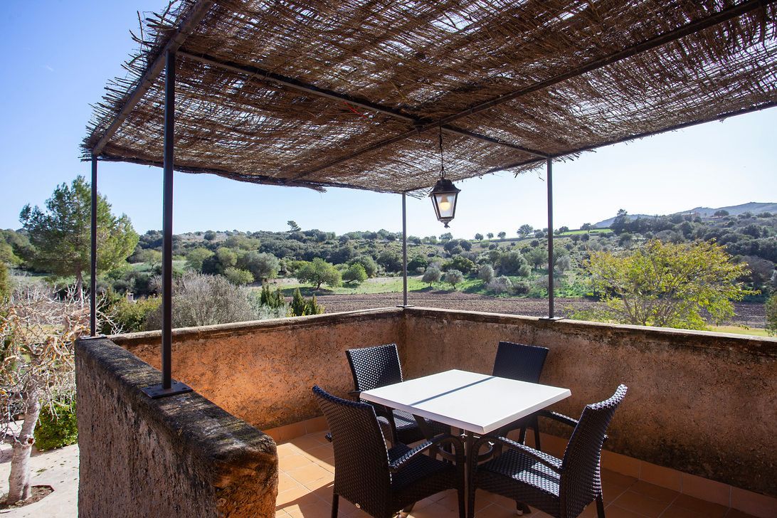 Eine Terrasse mit Tisch und Stühlen unter einem Baldachin.