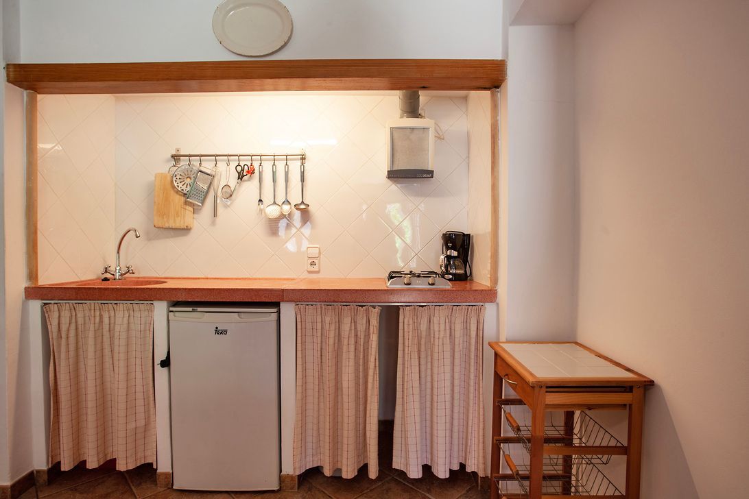 Eine kleine Küche mit Kühlschrank, Spüle und Tisch.