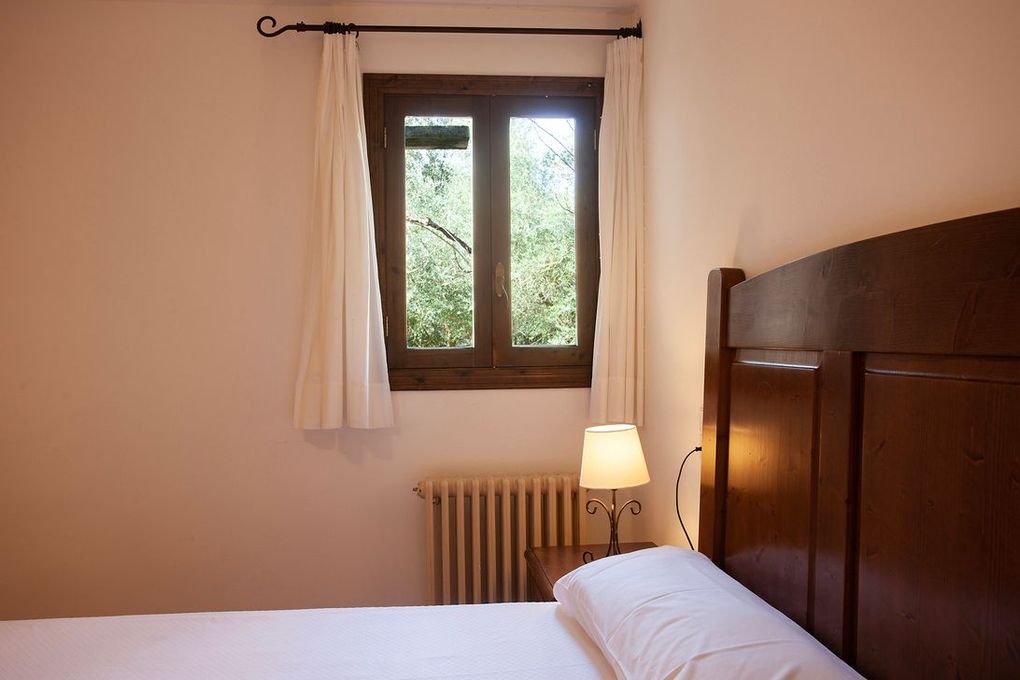 Un dormitorio con una cama, una lámpara y una ventana.