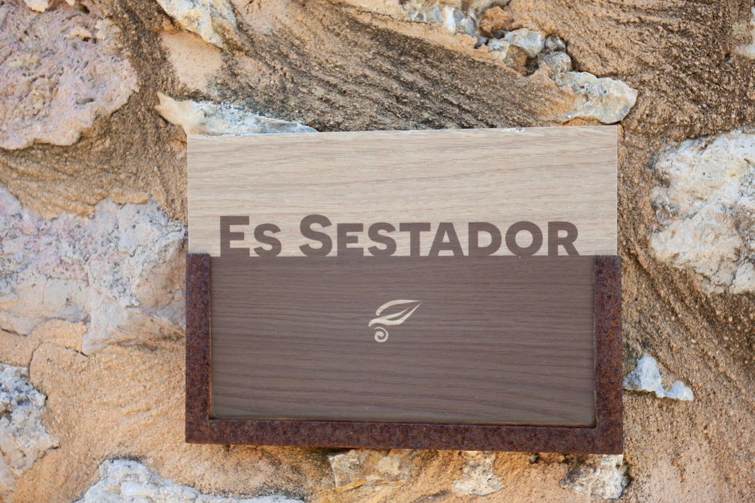 A wooden sign on a stone wall says es sestador