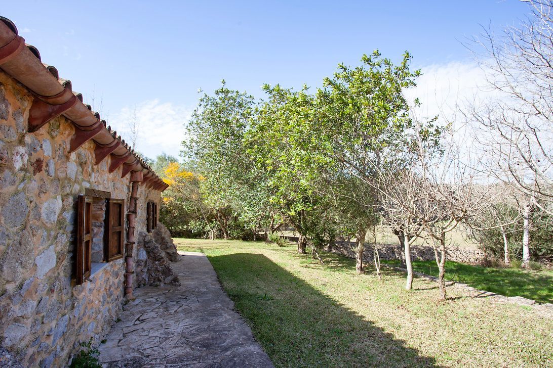 A stone building with a path leading to it and trees in the background.