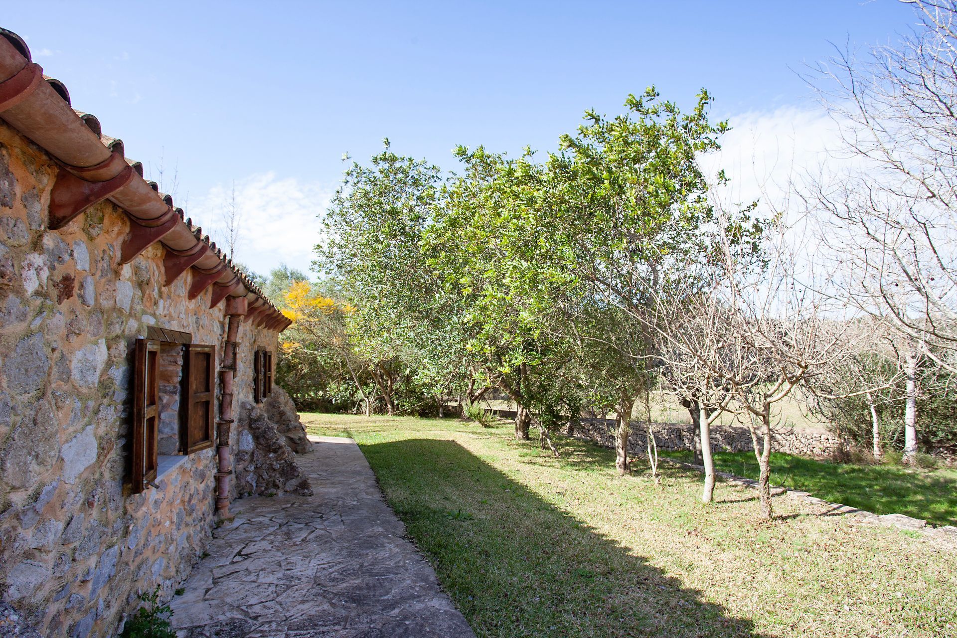 A stone building with a path leading to it and trees in the background.