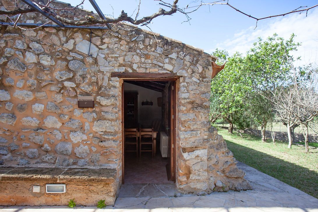 A stone building with a wooden door and a table and chairs inside.