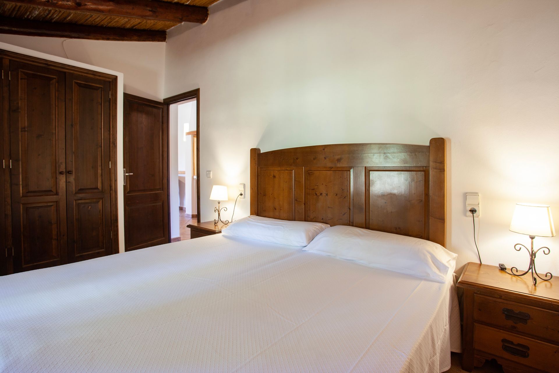 A bedroom with a large bed and a wooden headboard