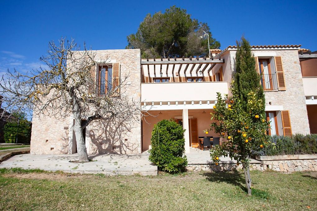 Una gran casa de piedra con un balcón y un árbol delante.