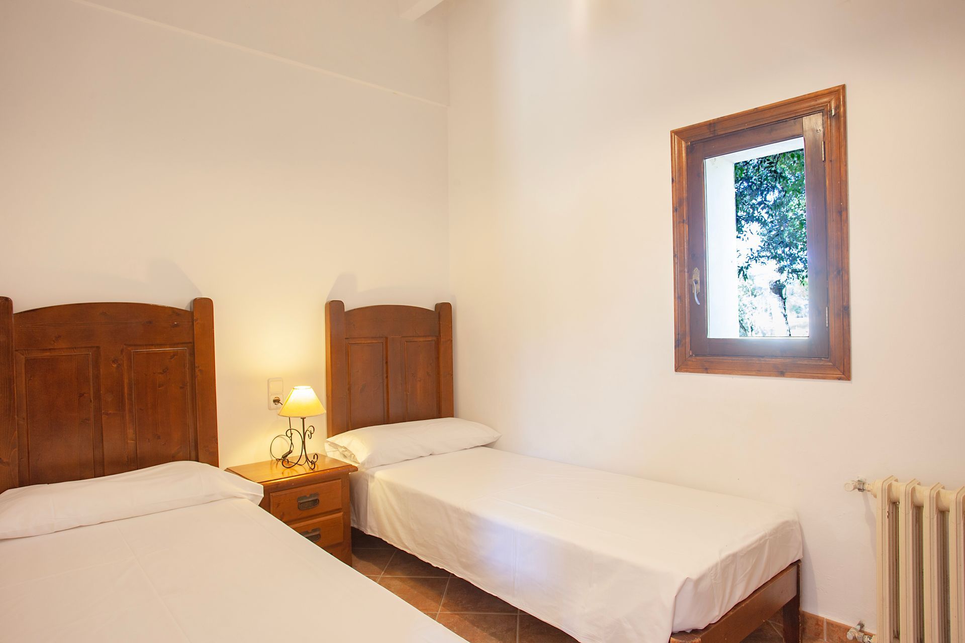 A bedroom with two beds , a nightstand and a window.