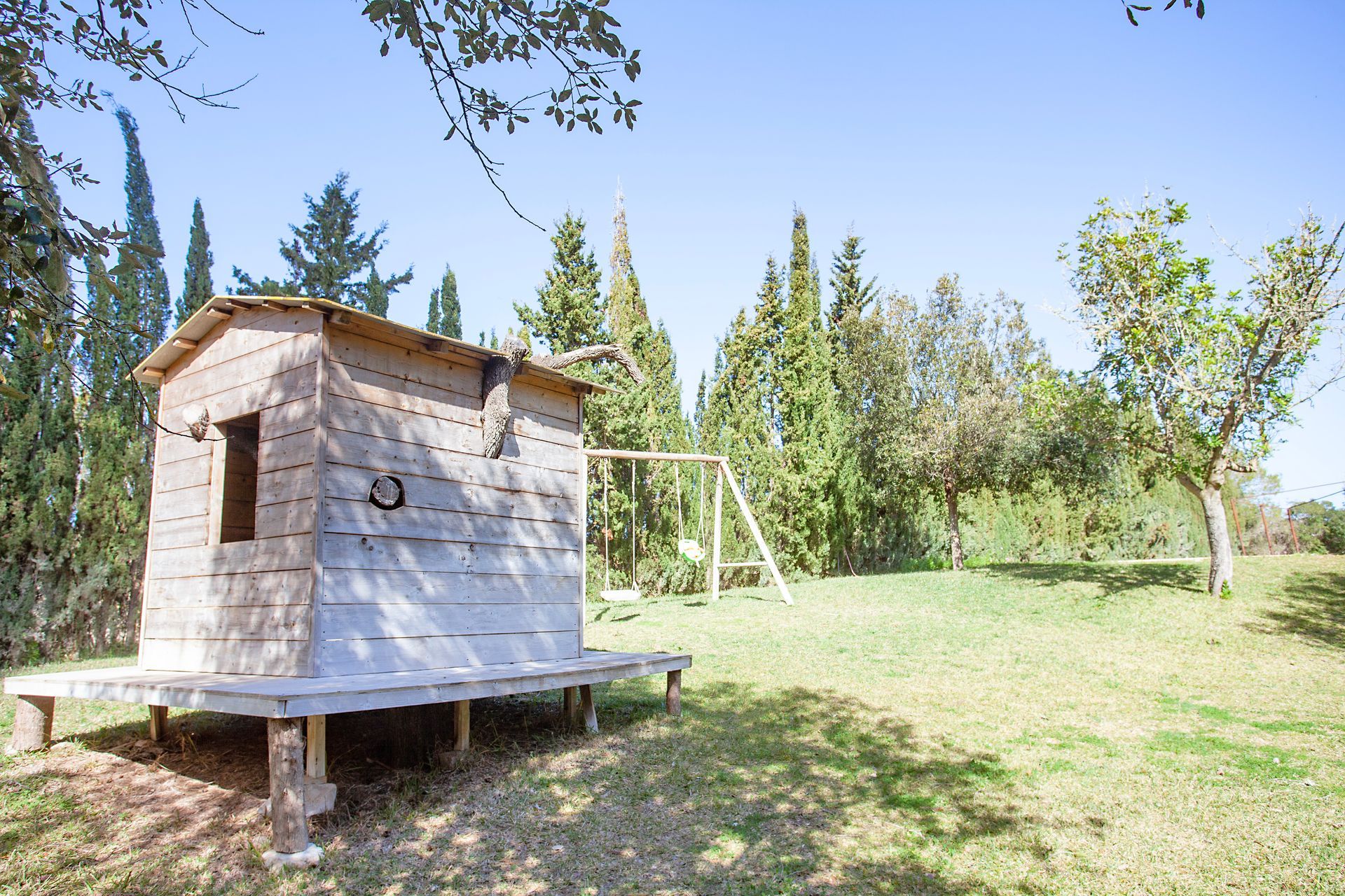 A small wooden house is sitting in the middle of a grassy field.