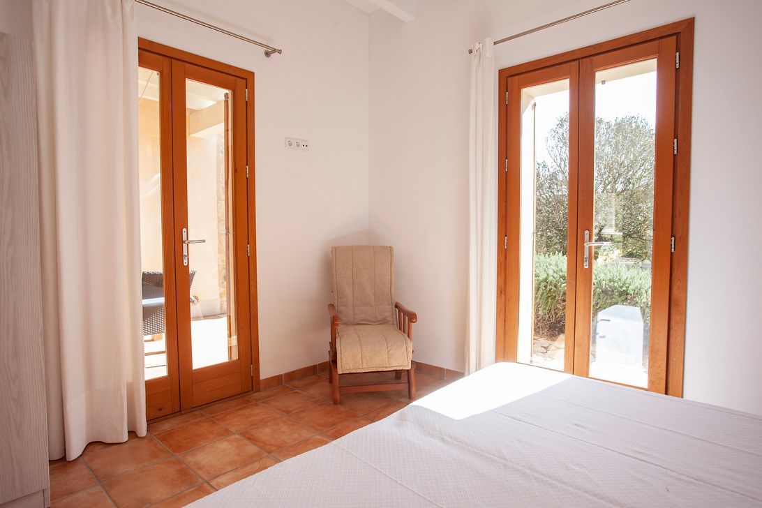 Un dormitorio con cama, silla y puertas corredizas de vidrio.