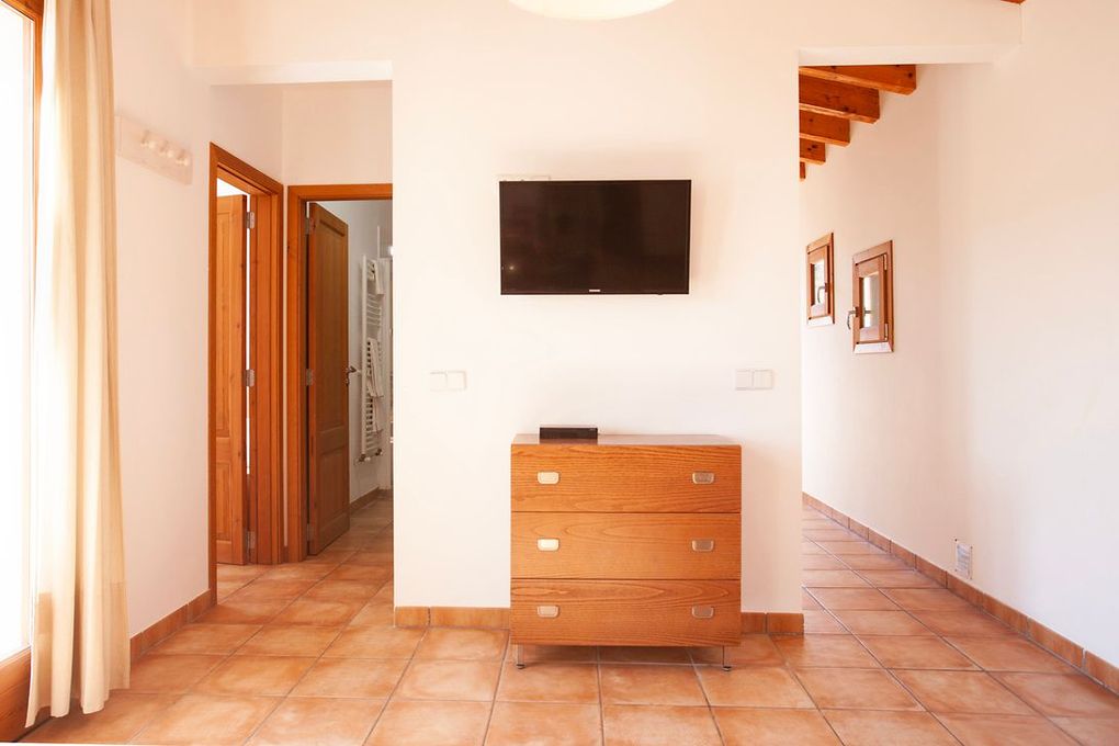 Una sala de estar con una cómoda y un televisor de pantalla plana en la pared.