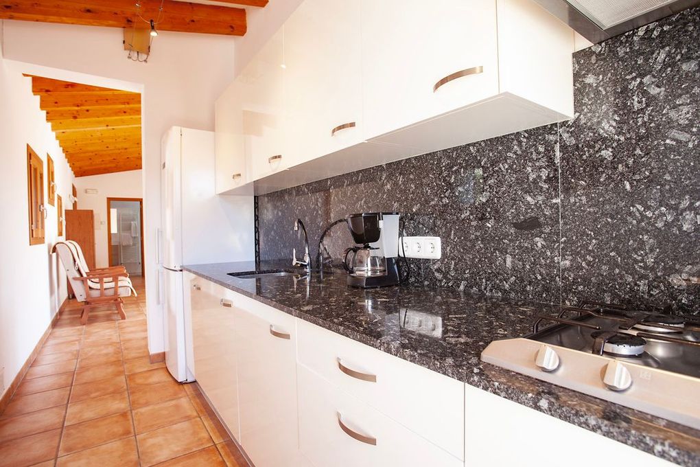 Una cocina con encimeras de granito y gabinetes blancos.