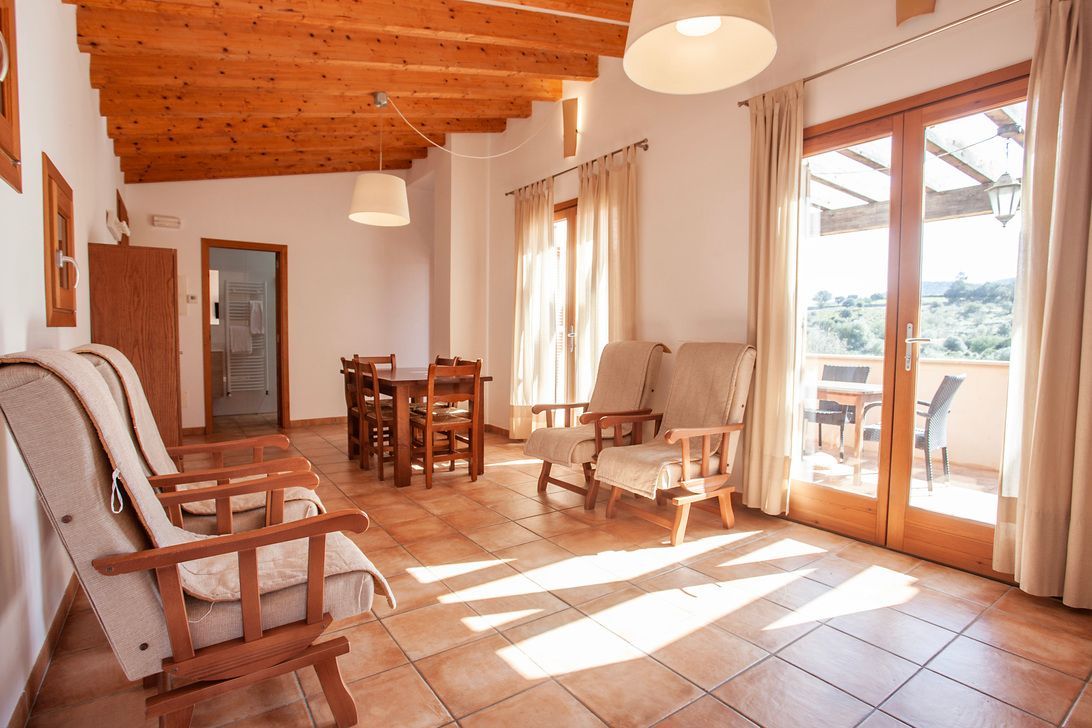 Ein Wohnzimmer mit Couch, Stühlen, Tisch und Balkon.