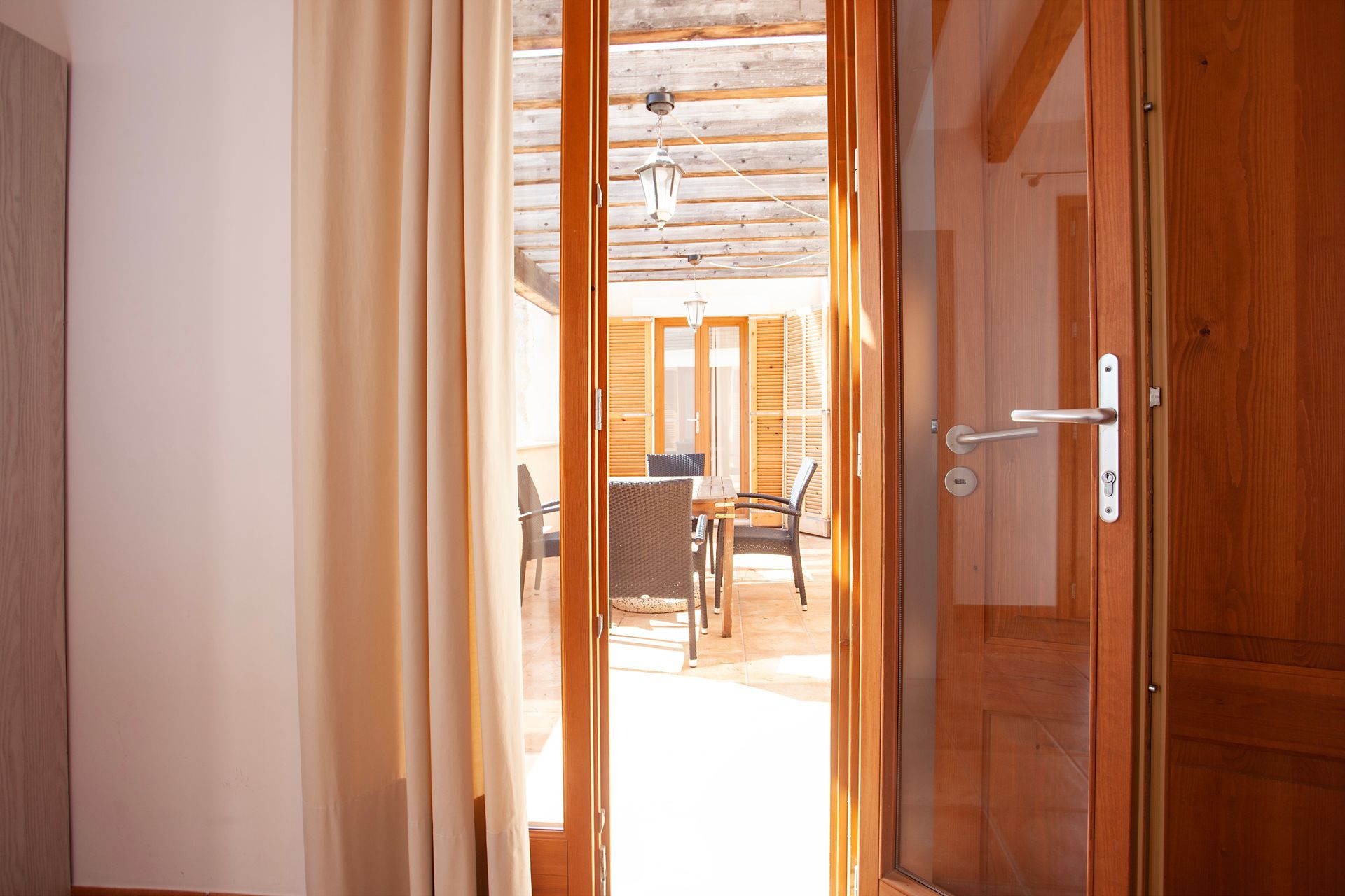 A wooden door is open to a living room with a table and chairs.