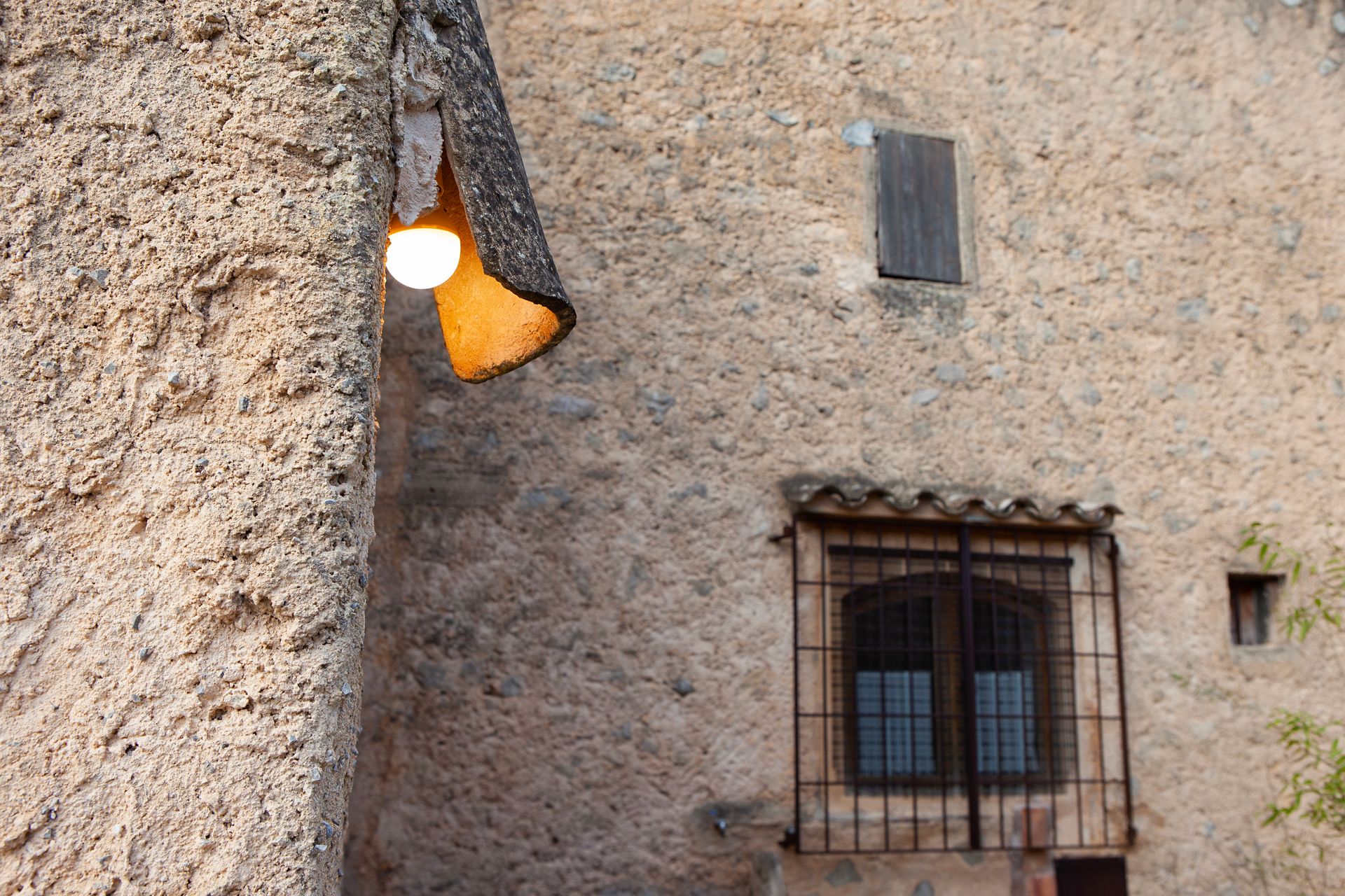 A brick wall with a window and a lamp on it